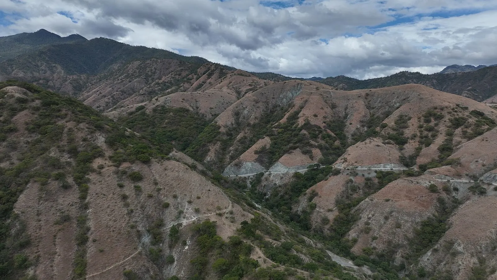 Laderas de montaña cubiertas de arbustos bajo un cielo nublado