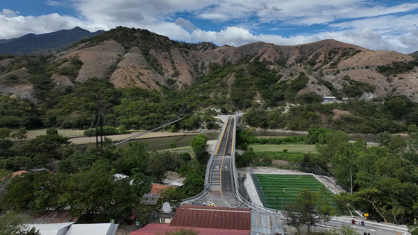 Sierra con vegetación verde y un puente sobre el río