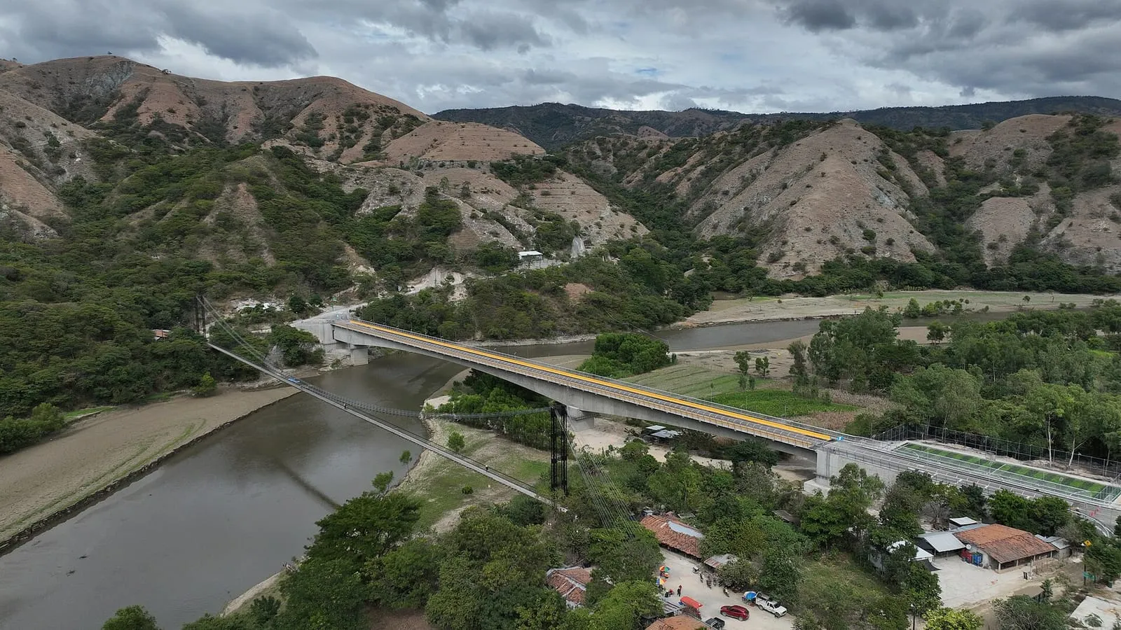 Valle con un río ancho y montañas al fondo en un día nublado